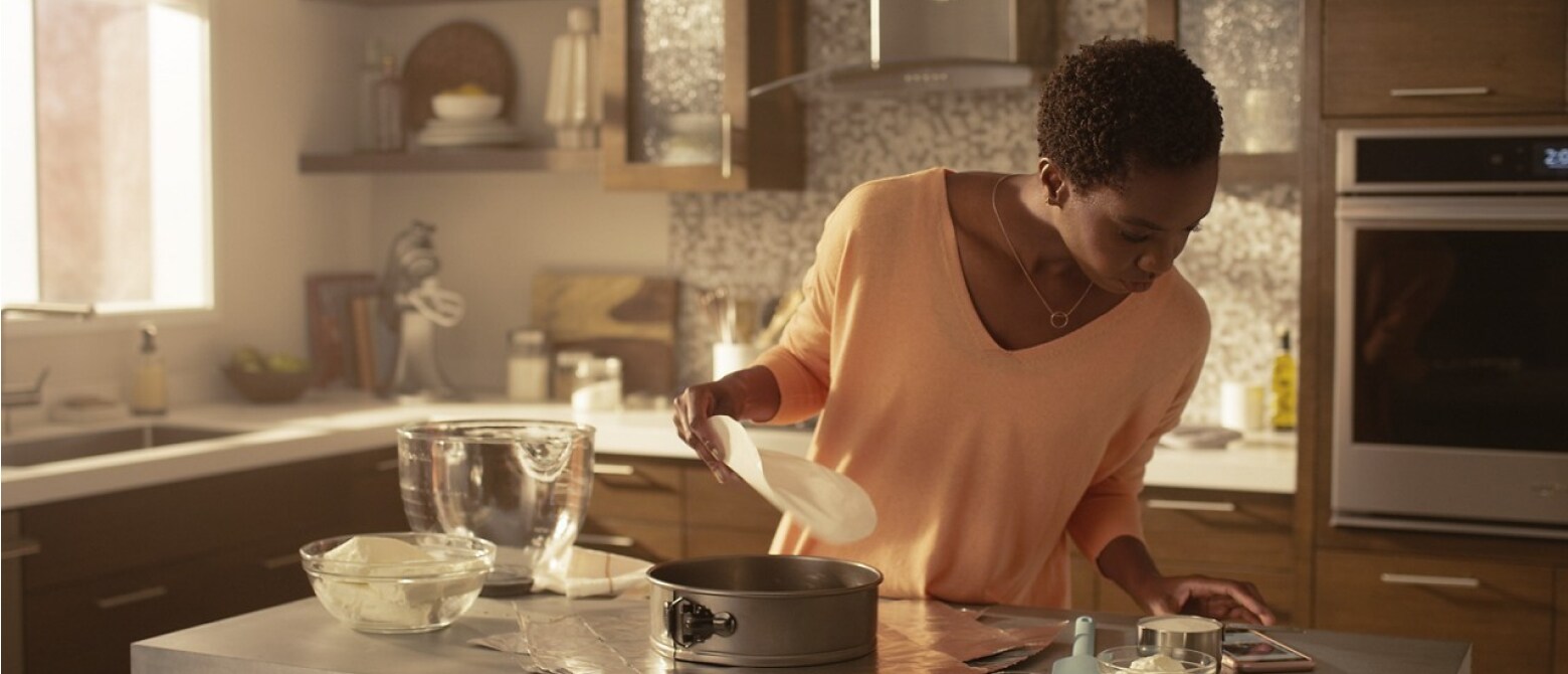 Woman in kitchen reading recipe on her phone