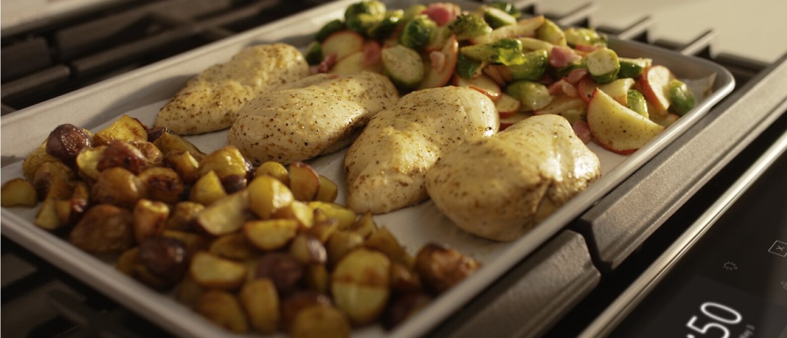 Close up of a sheet pan with chicken breasts and vegetables