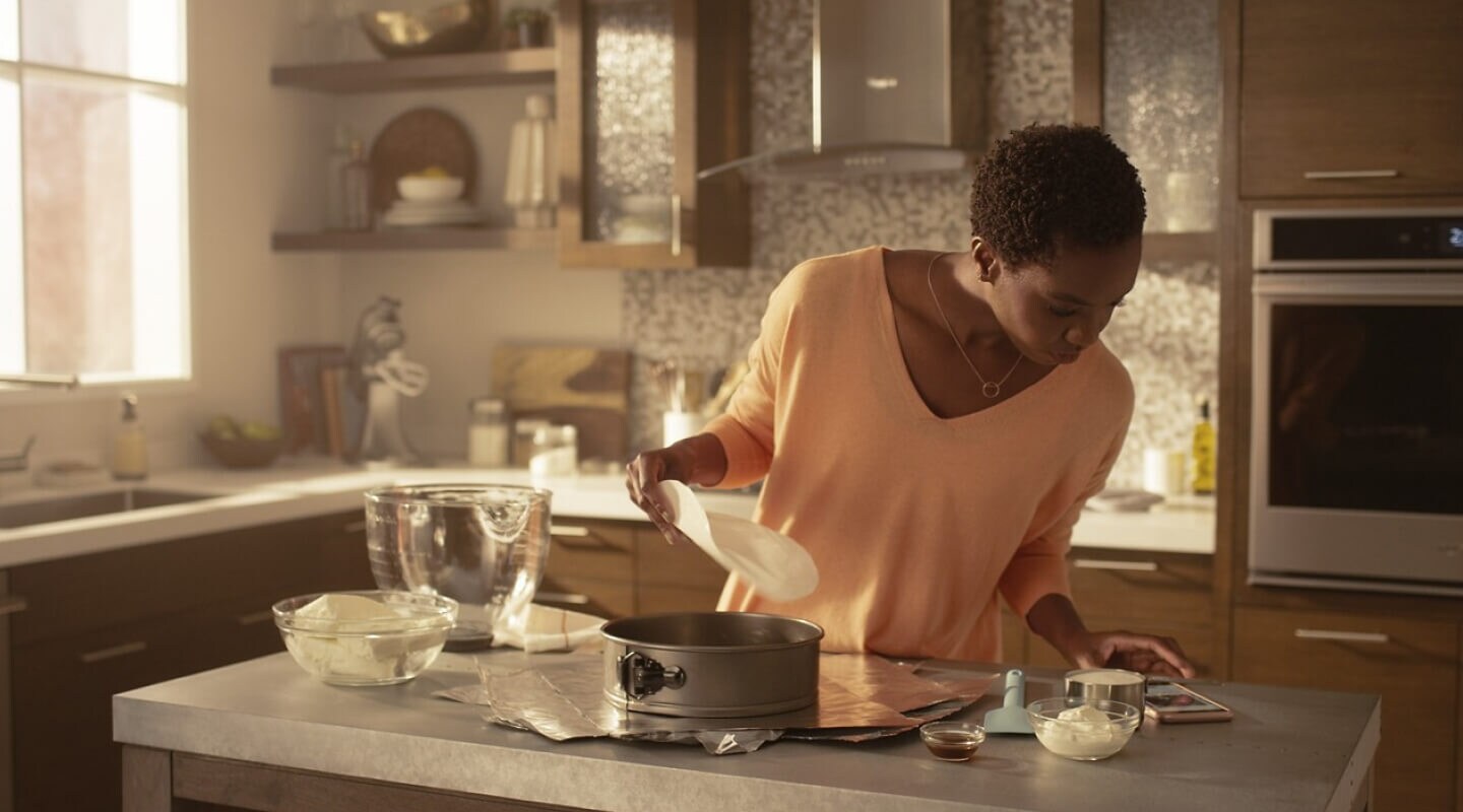 Woman in kitchen reading recipe on her phone 