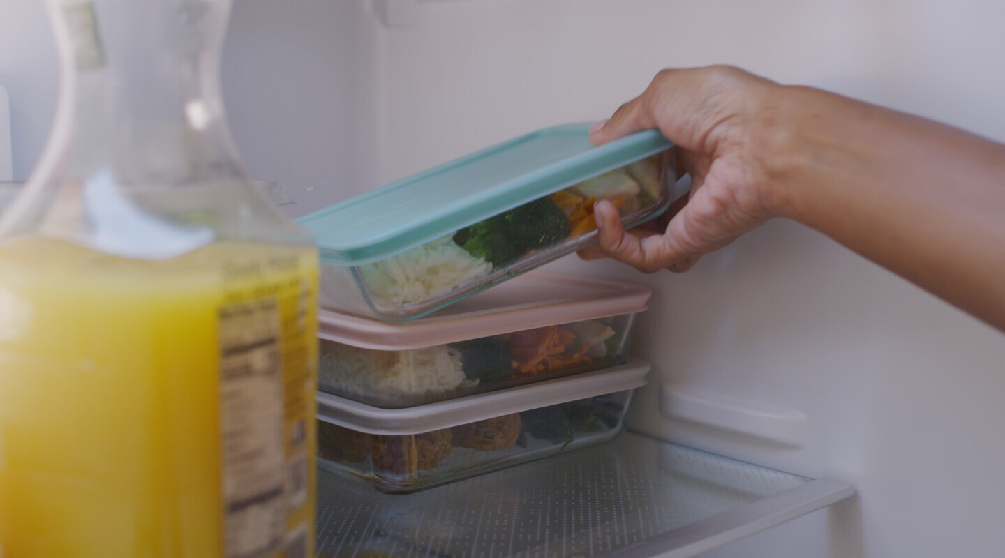 Hand storing meal prep container into fridge