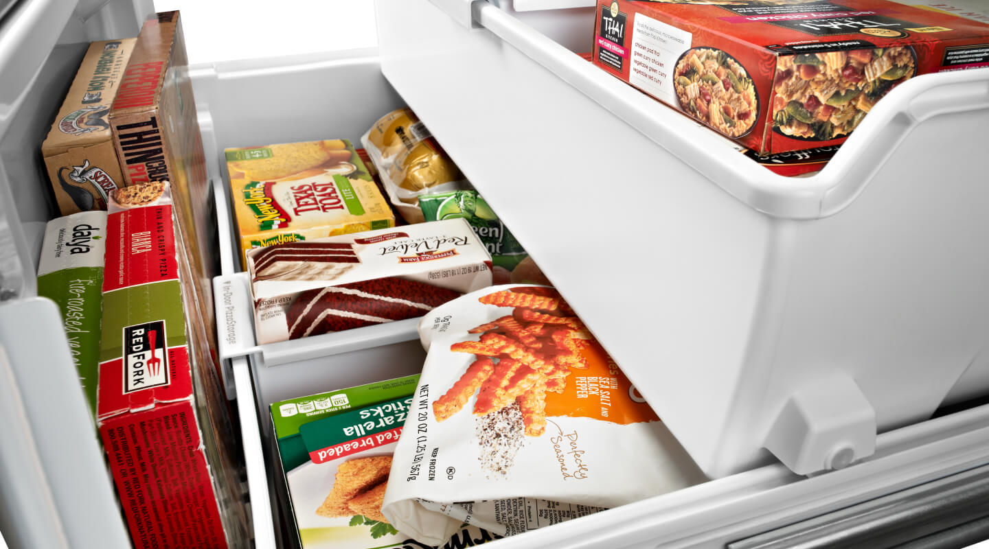 Bottom freezer drawer opened showing organized freezer bins