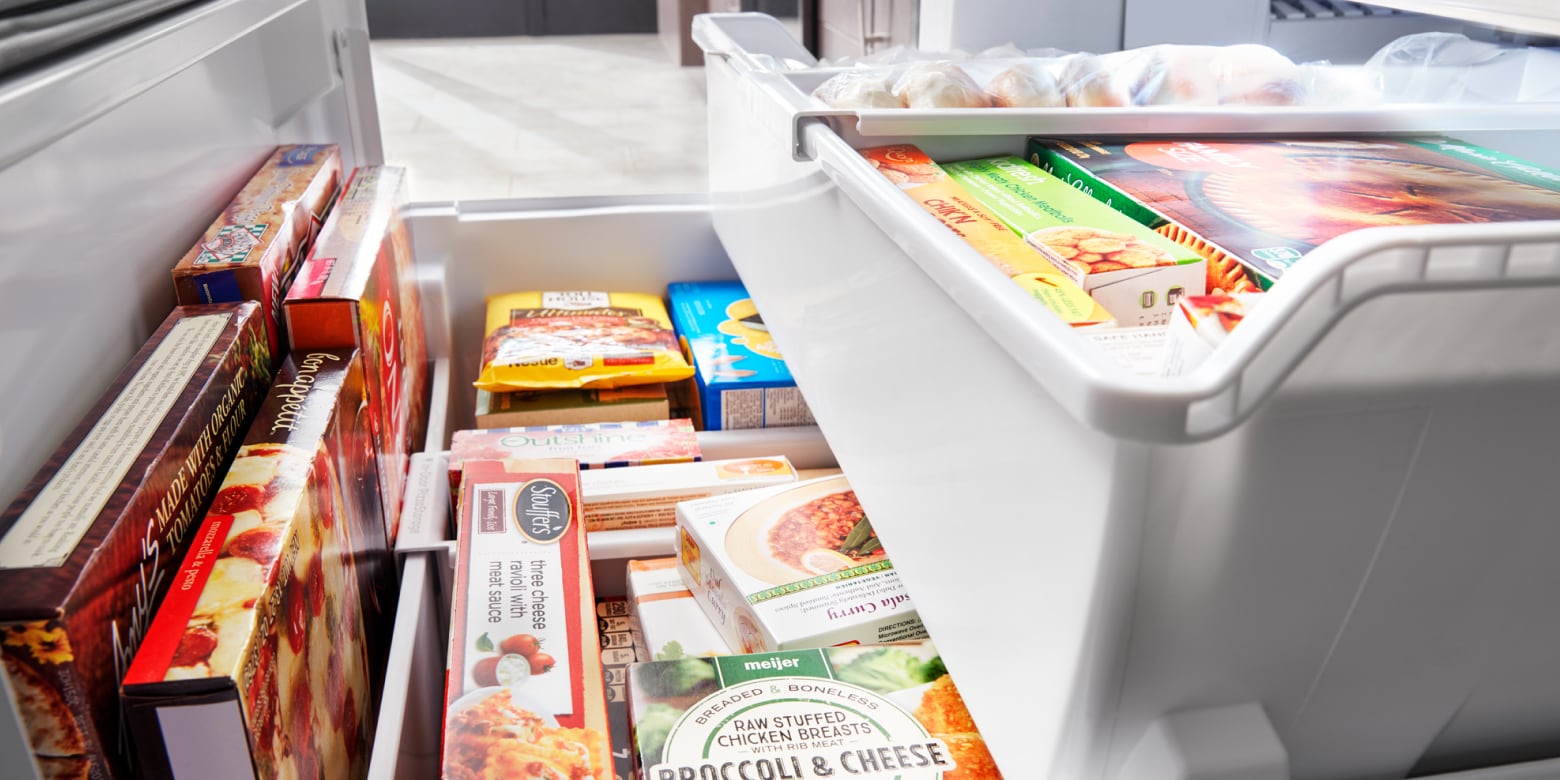 Bottom freezer drawer opened showing organized freezer bins