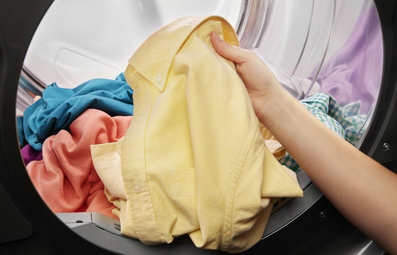 Hand pulling yellow shirt out of a dryer Hand pulling yellow shirt out of a dryer