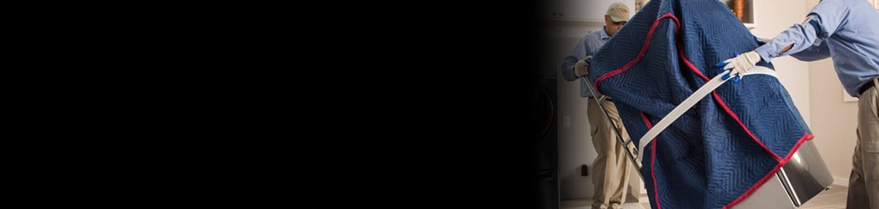 Person moving large appliance covered in a moving blanket with a hand truck