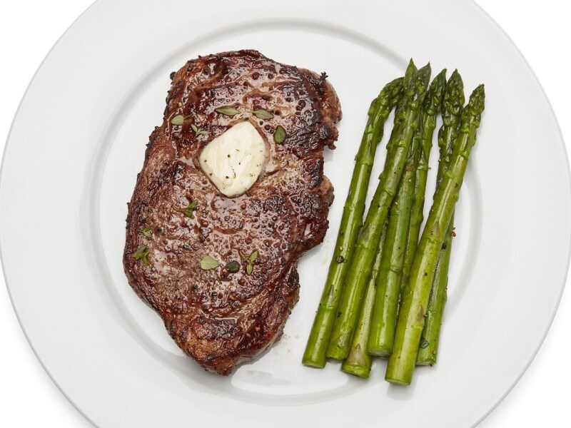 Plate of steak with melted butter and asparagus