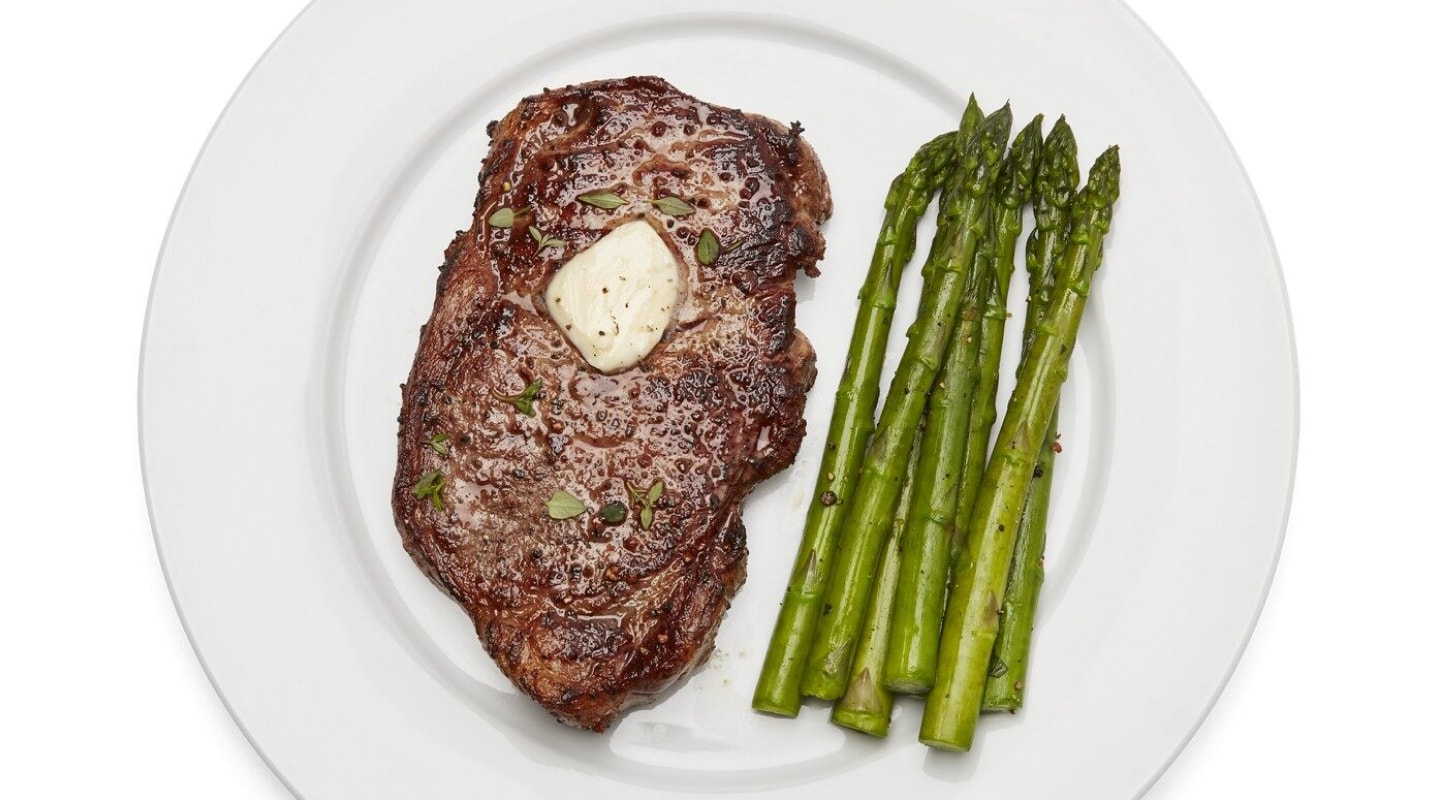 Plate of steak with melted butter and asparagus Plate of steak with melted butter and asparagus