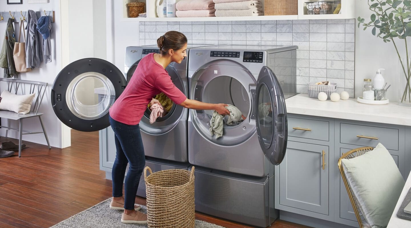 A woman moving clothes from her washer to her dryer A woman moving clothes from her washer to her dryer