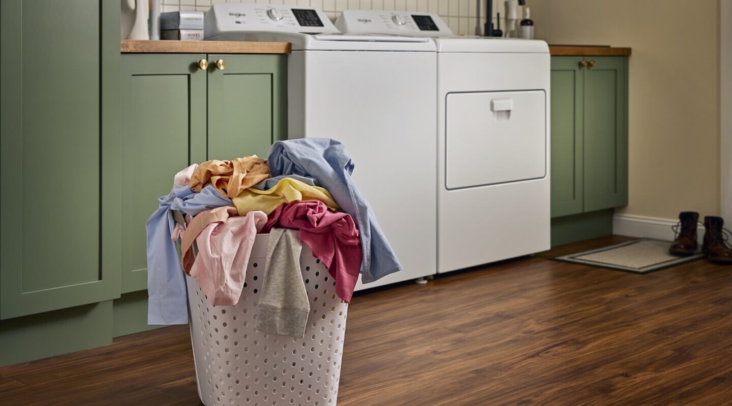 Clothes in a basket in front of a white Whirlpool® Washer and Dryer Clothes in a basket in front of a white Whirlpool® Washer and Dryer