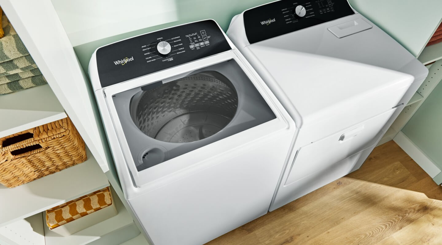 A laundry area with a white Whirlpool® Top-Load Washer and Dryer