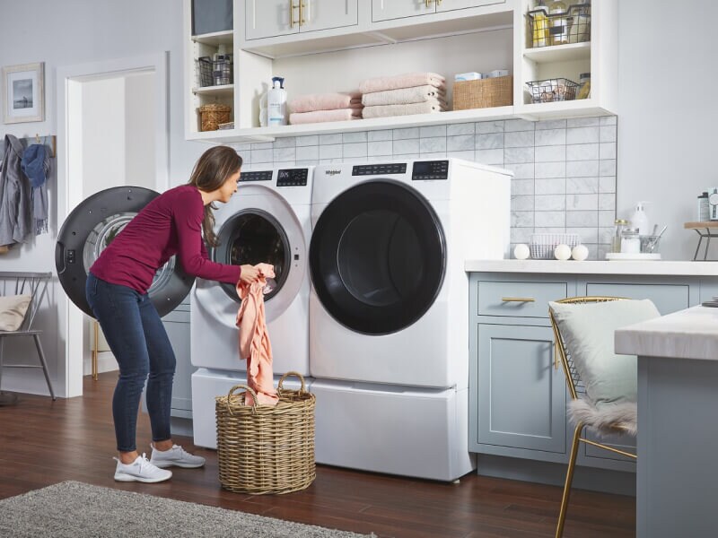 A woman loading clothes into a Whirlpool® Washer A woman loading clothes into a Whirlpool® Washer