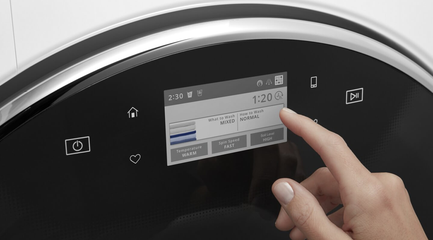 A person operating the control pad on their washing machine A person operating the control pad on their washing machine