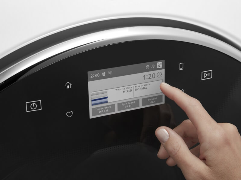 A person operating the control pad on their washing machine A person operating the control pad on their washing machine