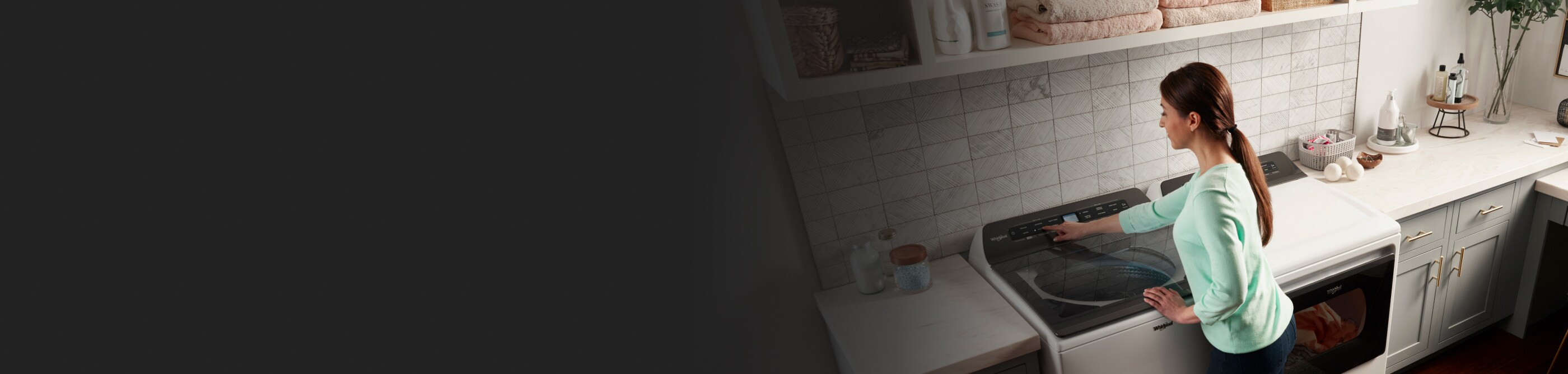 A woman selects a cycle on a top load washer