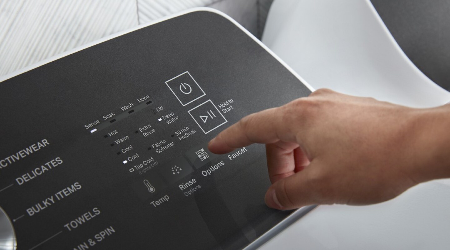 Person selecting settings on a washer control panel Person selecting settings on a washer control panel