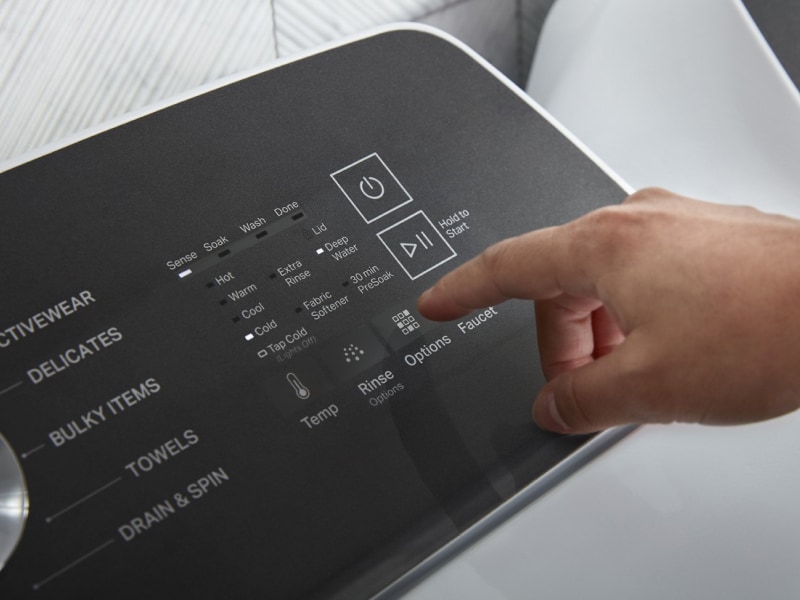 Person selecting settings on a washer control panel Person selecting settings on a washer control panel