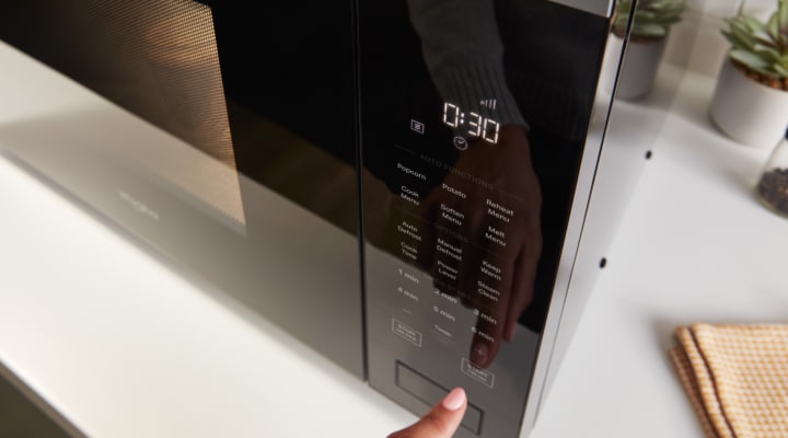 Person operating the control panel of a microwave Person operating the control panel of a microwave