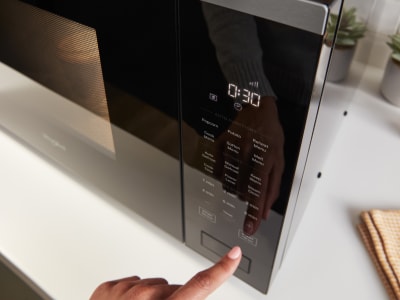 Person operating the control panel of a microwave Person operating the control panel of a microwave