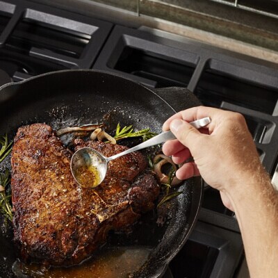 Someone drizzling juices over meat