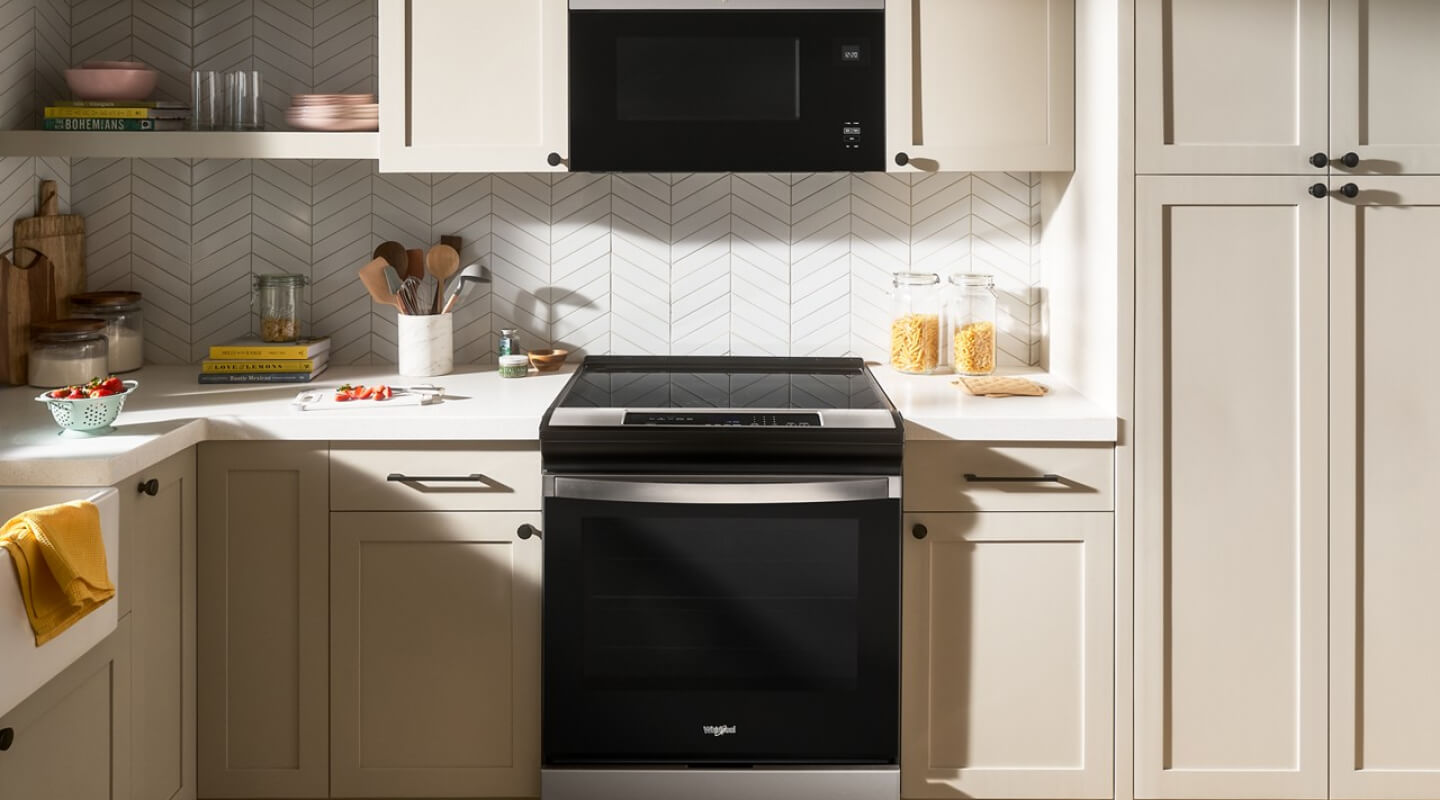 A kitchen with a black Whirlpool ® Induction Range with a microwave above it