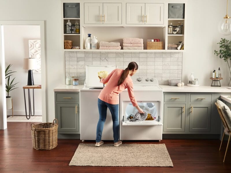 Person moving laundry from a washer to a dryer Person moving laundry from a washer to a dryer