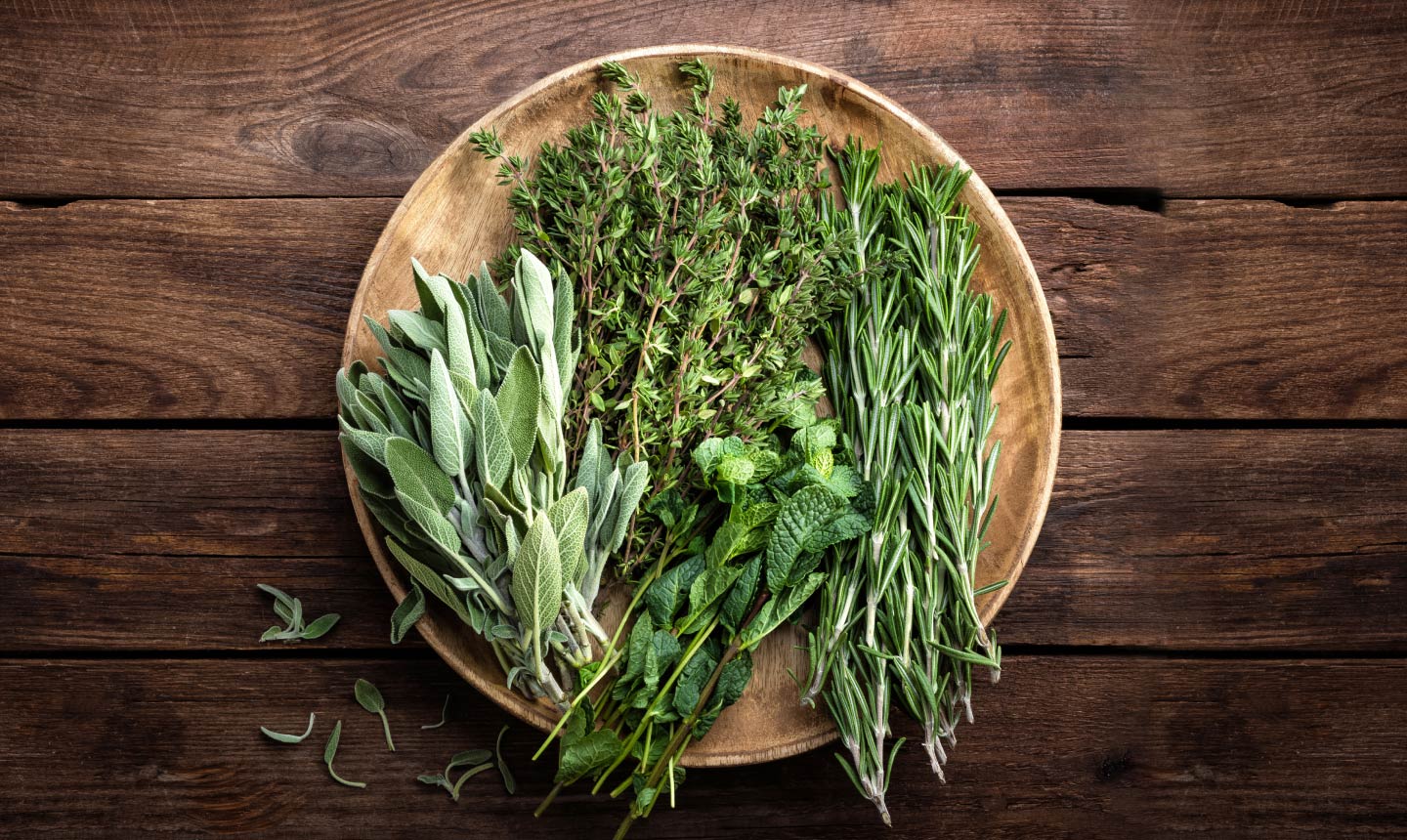 Fresh herbs on a wooden plate on a wooden table