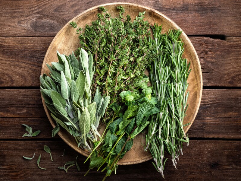 Fresh herbs on a wooden plate on a wooden table