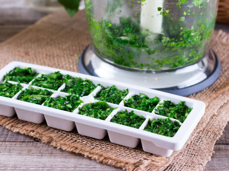 Chopped herbs in a white ice tray 