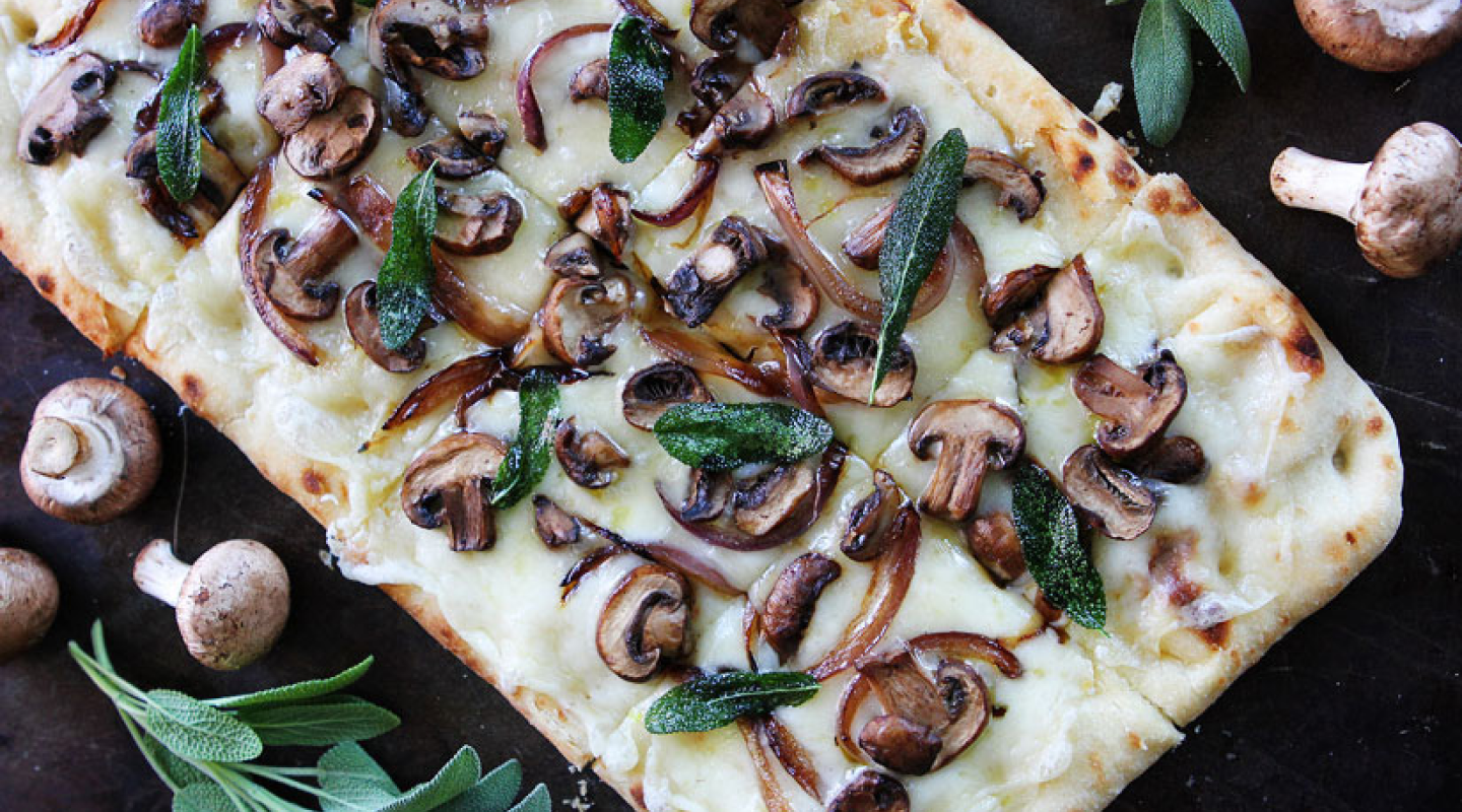 Flatbread pizza topped with cheese, mushrooms and herbs Flatbread pizza topped with cheese, mushrooms and herbs