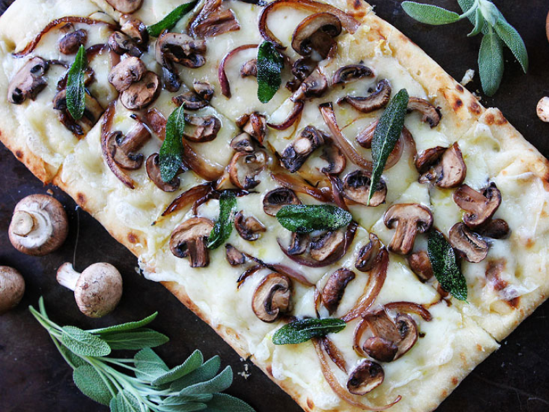 Flatbread pizza topped with cheese, mushrooms and herbs Flatbread pizza topped with cheese, mushrooms and herbs