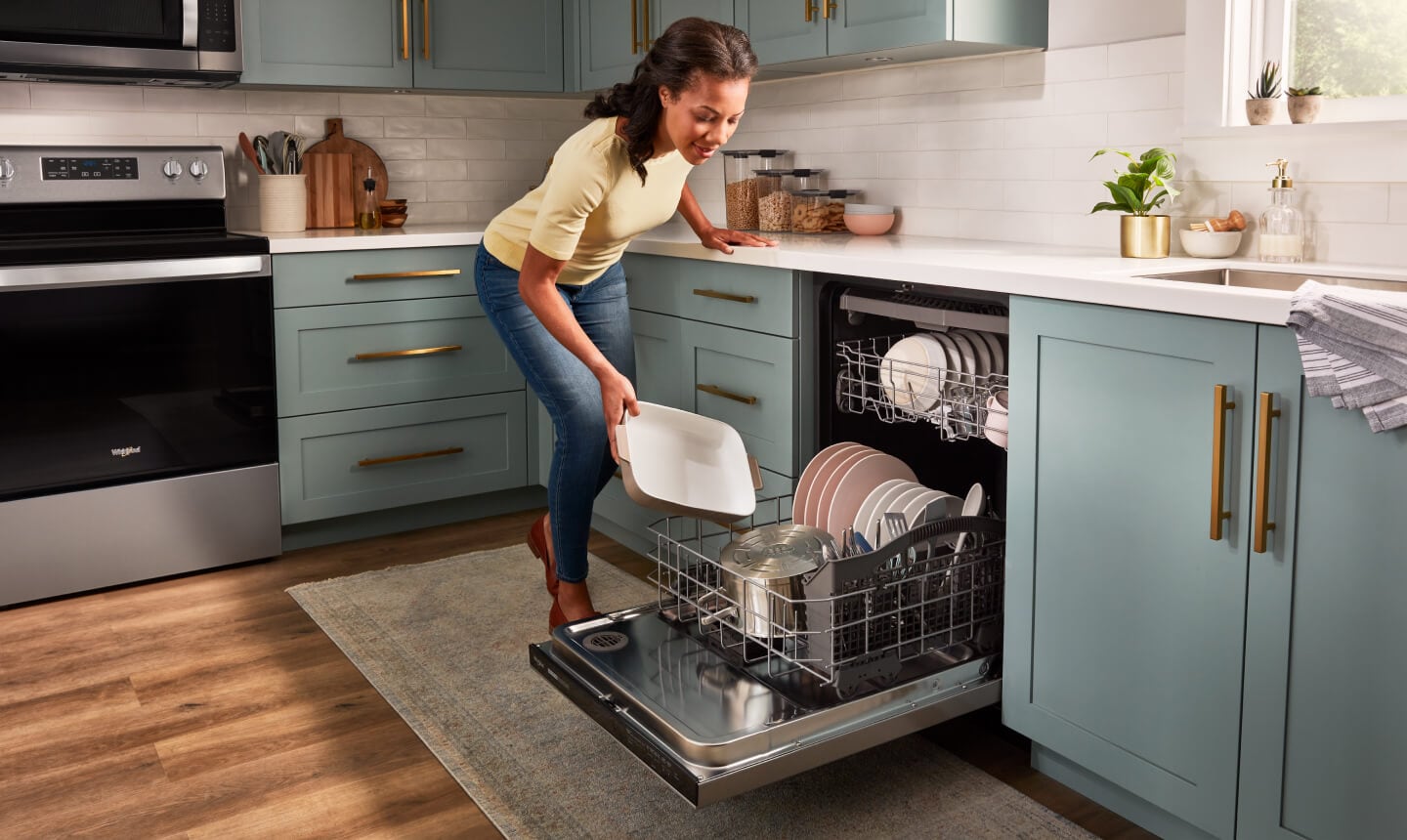 A person loading cookware into a dishwasher