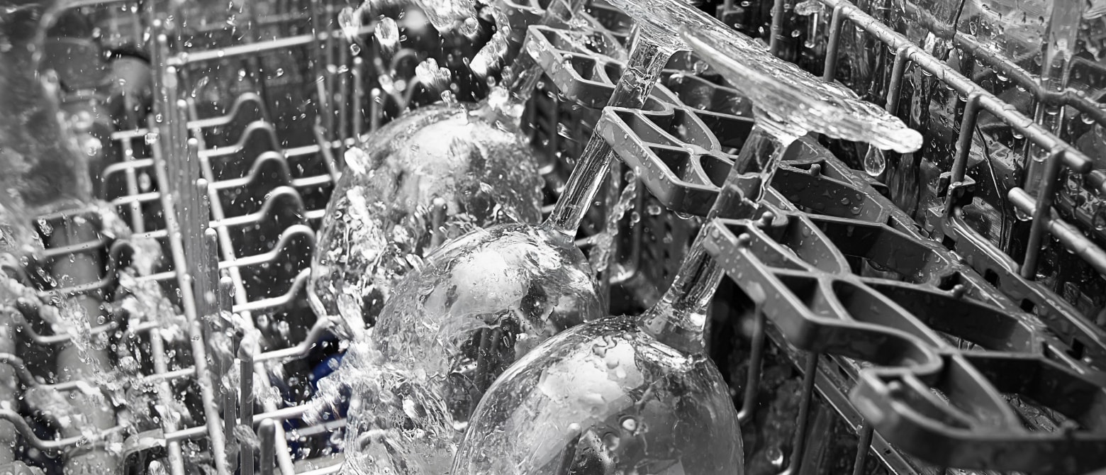 A closeup of wine glasses being cleaned in a dishwasher A closeup of wine glasses being cleaned in a dishwasher