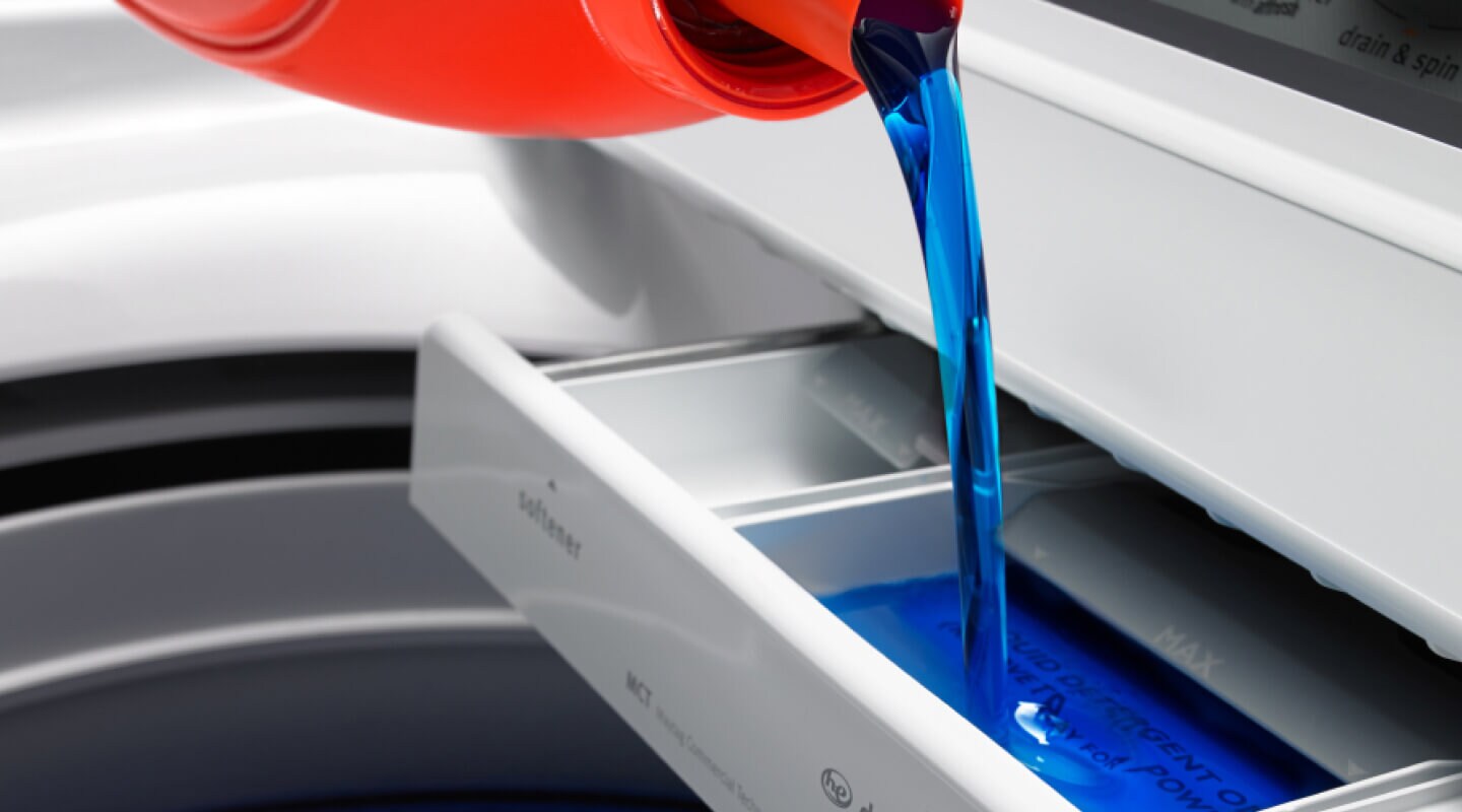 Liquid laundry detergent pouring into washer