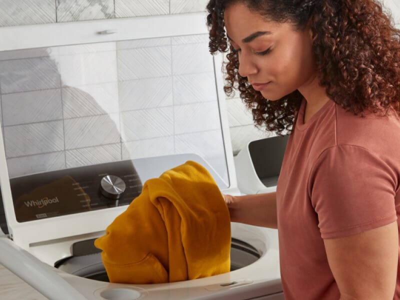 Person pulling laundry out of Whirlpool® Washer