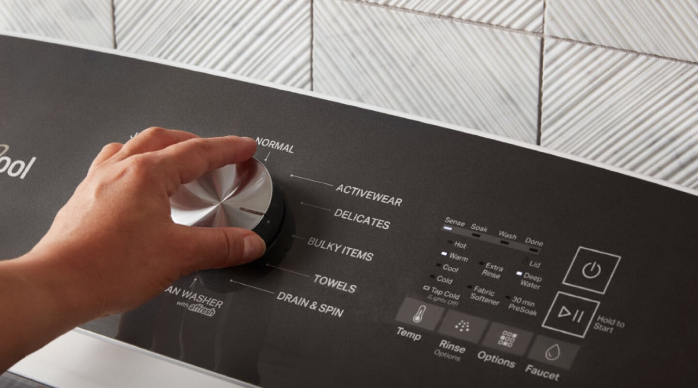Hand turning the knob on a Whirlpool® Top Load Washer