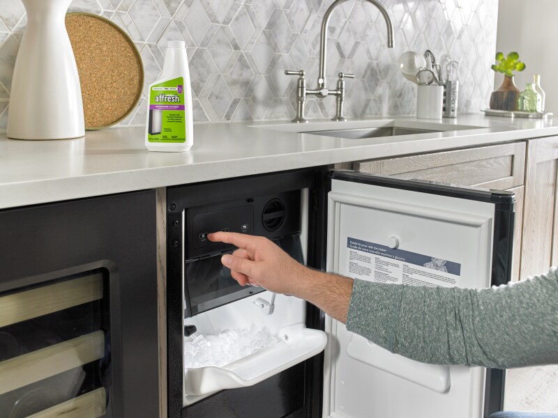 Person opening a built-in icemaker next to affresh® cleaner Person opening a built-in icemaker next to affresh® cleaner