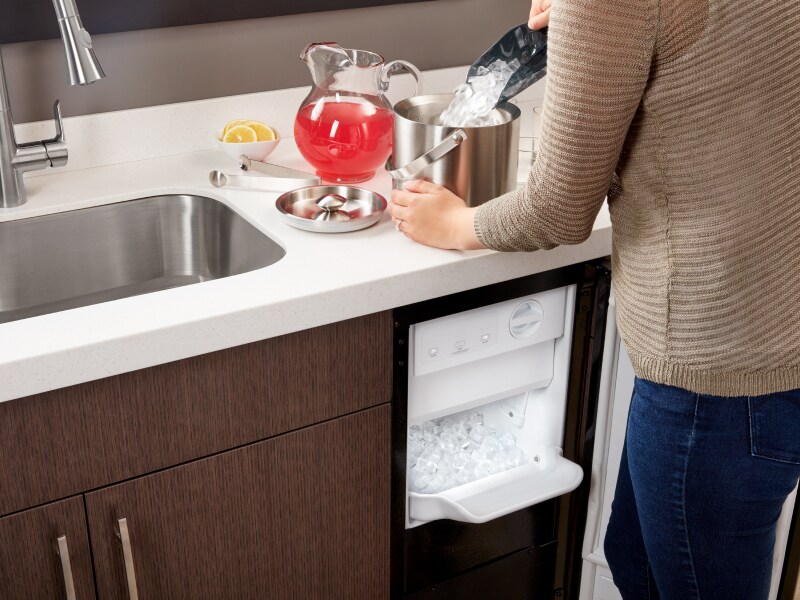 Person filling an ice bucket from a Whirlpool® icemaker Person filling an ice bucket from a Whirlpool® icemaker