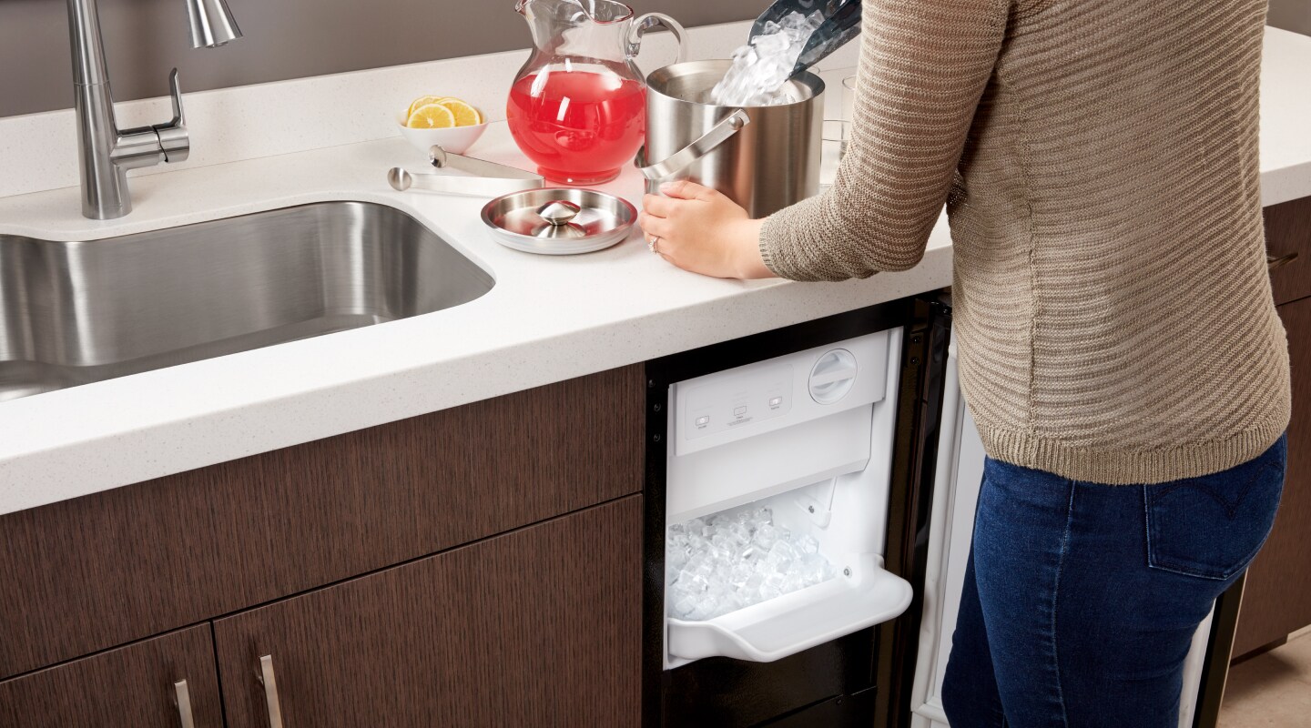 Person filling an ice bucket from a Whirlpool® icemaker Person filling an ice bucket from a Whirlpool® icemaker