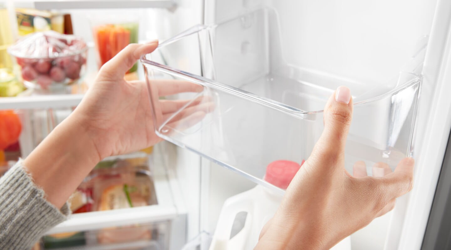 Person adjusting a shelf on the inside door of a refrigerator Person adjusting a shelf on the inside door of a refrigerator