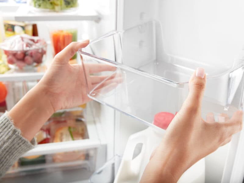 Person adjusting a shelf on the inside door of a refrigerator Person adjusting a shelf on the inside door of a refrigerator