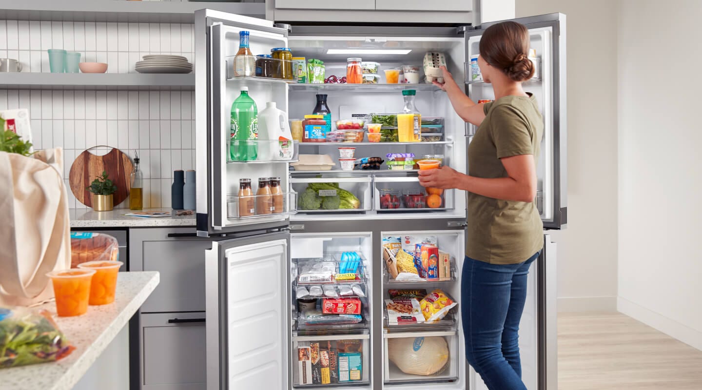 A person putting food in her open refrigerator A person putting food in her open refrigerator