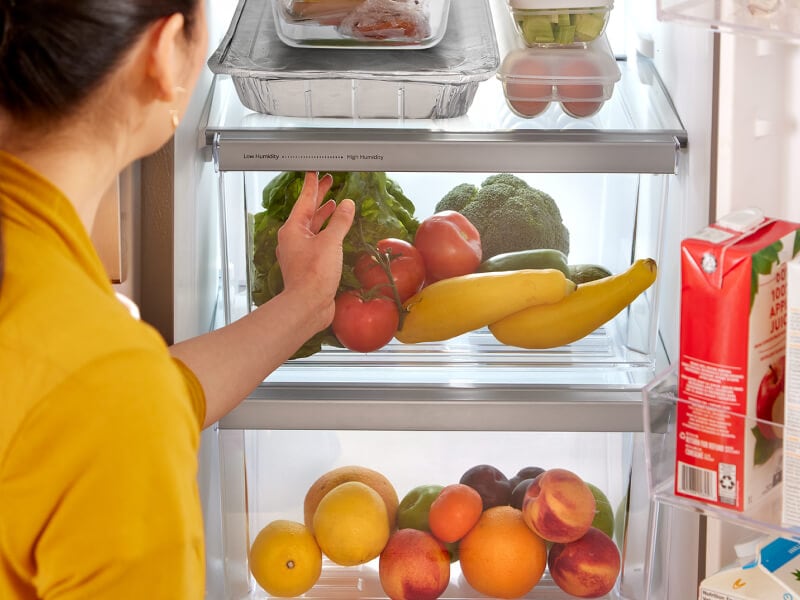 Someone adjusting the humidity setting on a refrigerator storage drawer Someone adjusting the humidity setting on a refrigerator storage drawer