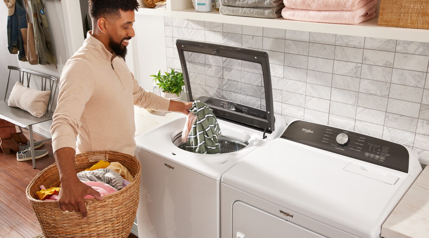 Person adding clothes into a top load Whirlpool® Washer Person adding clothes into a top load Whirlpool® Washer
