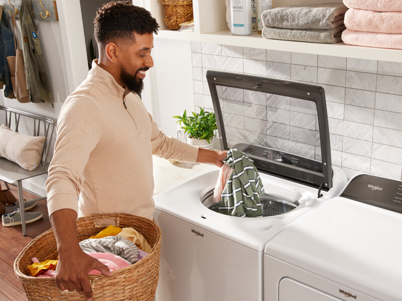 Person adding clothes into a top load Whirlpool® Washer Person adding clothes into a top load Whirlpool® Washer