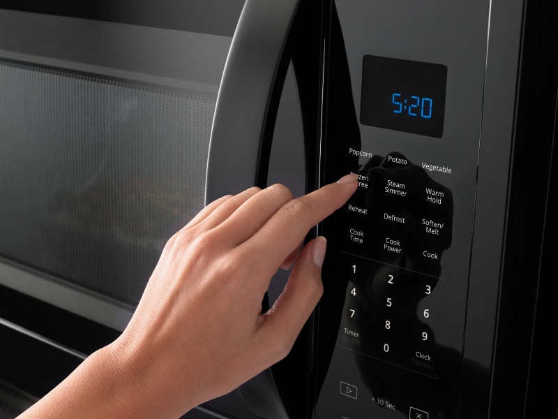 Hand pressing a microwave display Hand pressing a microwave display