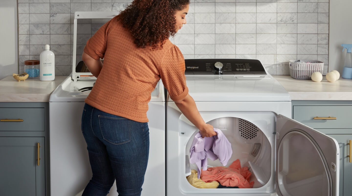 Person putting laundry into a dryer Person putting laundry into a dryer