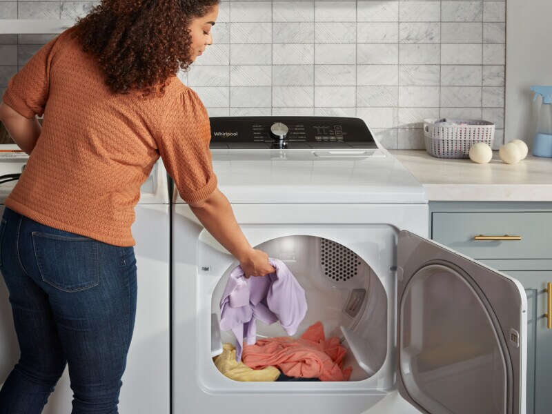 Person putting laundry into a dryer Person putting laundry into a dryer