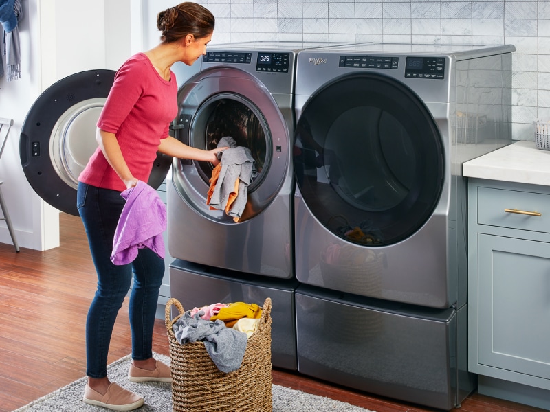 Person loading laundry into a slate gray Whirlpool® washing machine Person loading laundry into a slate gray Whirlpool® washing machine