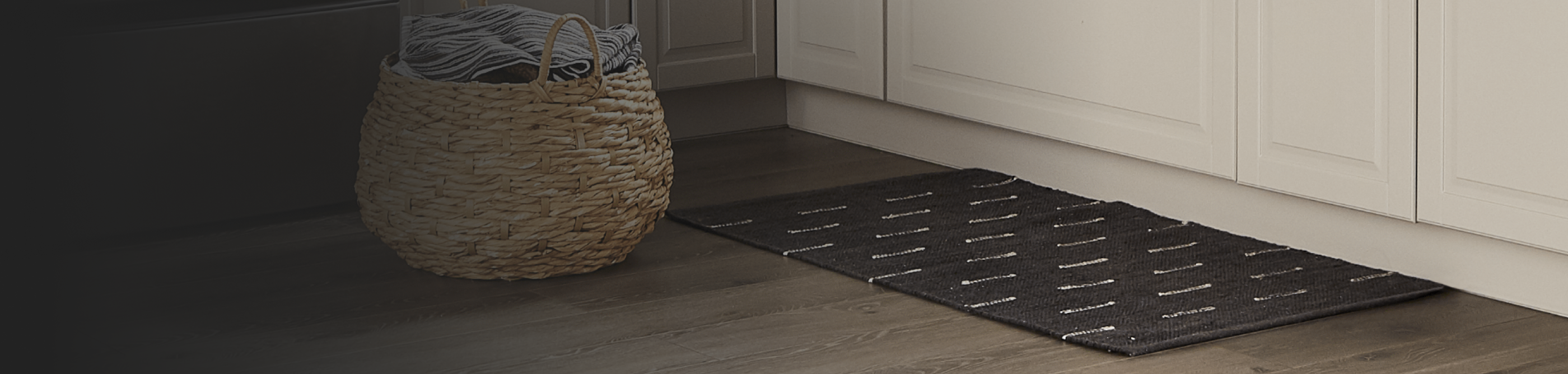Laundry basket full of clothes inside a laundry room next to a rug