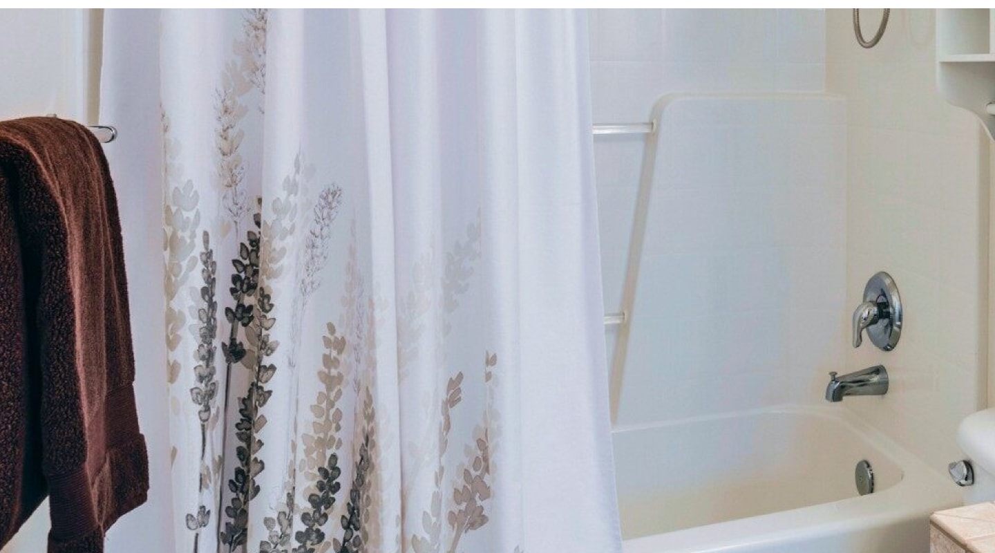 A hanging shower curtain with a design at the bottom. A hanging shower curtain with a design at the bottom.