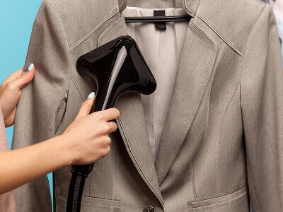 Person using a garment steamer on a suit jacket